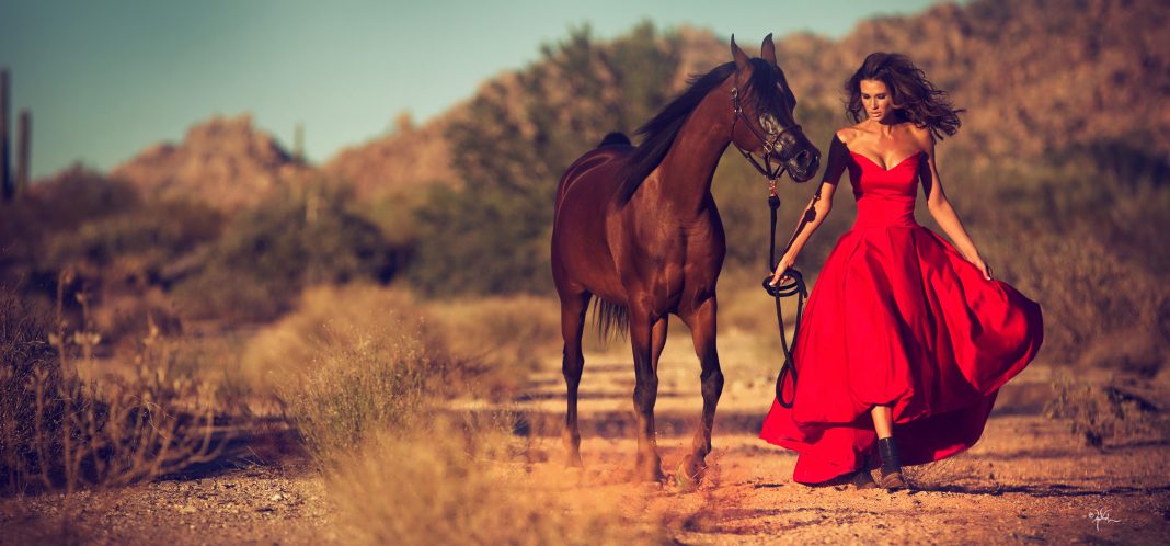 Glamorous woman walking in Arizona desert with Arabian horse